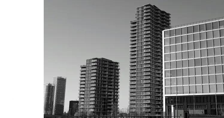 Black and white photo of modern high-rise buildings under a clear sky. The tall, geometric structures convey a sense of urban minimalism and calm.
